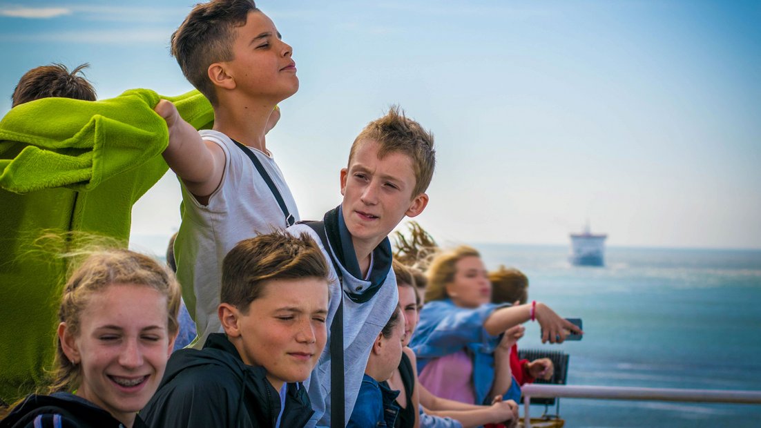 Les jeunes sur le pont d’un navire profitent de la vue.