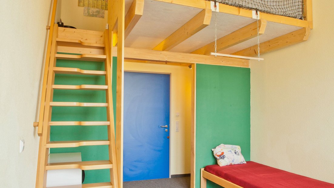 Chambre dans la maison de prairie avec lit et escalier en bois