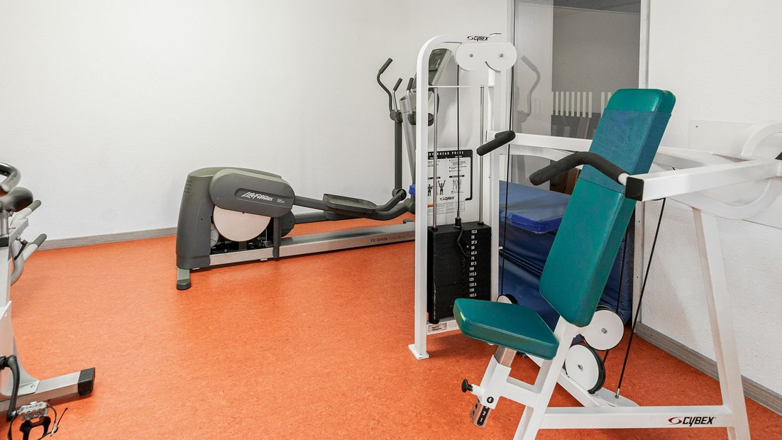 Salle de fitness avec banc de musculation et vélo elliptique